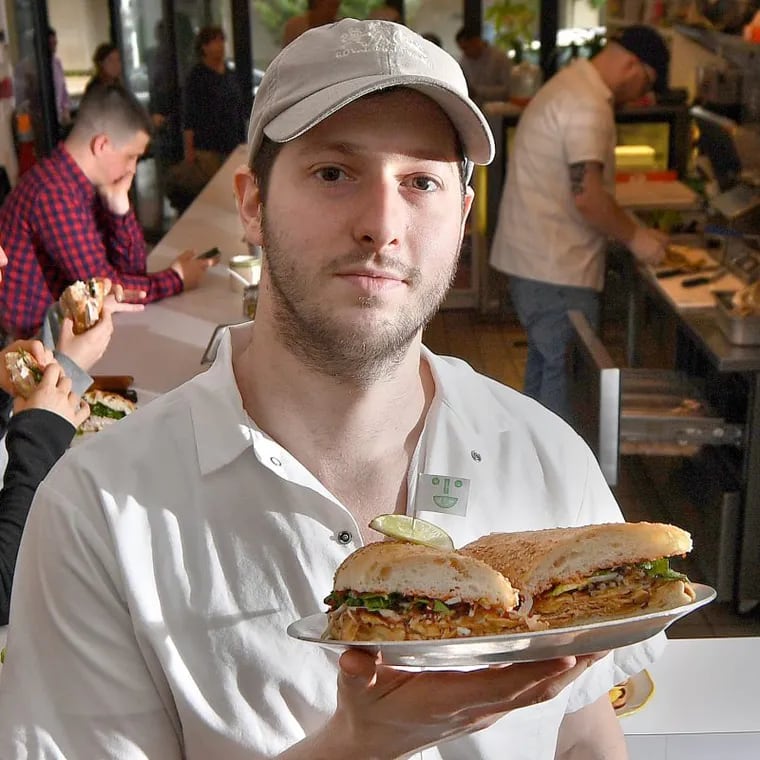 Matthew Cahn at Middle Child, holding a vegan Phoagie at the 11th Street location in 2018.
