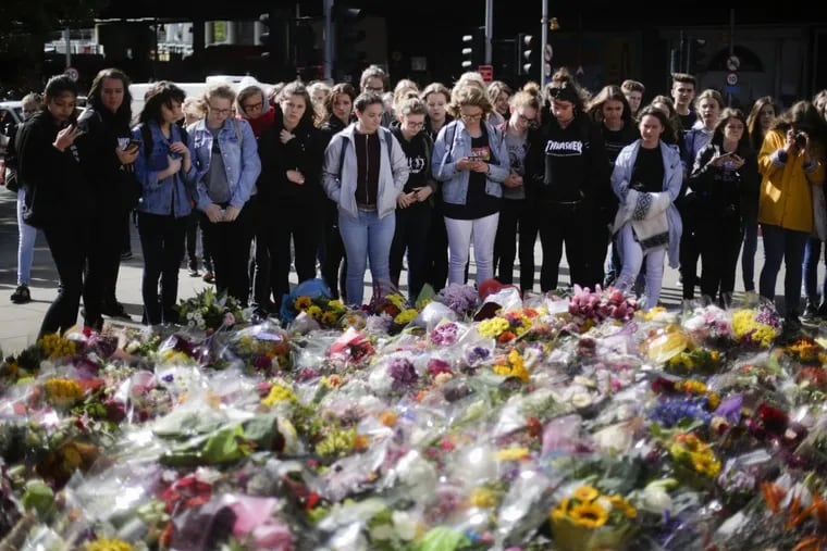 People look at floral tributes on London Bridge Wednesday in commemoration of the victims of last weekend’s attack.