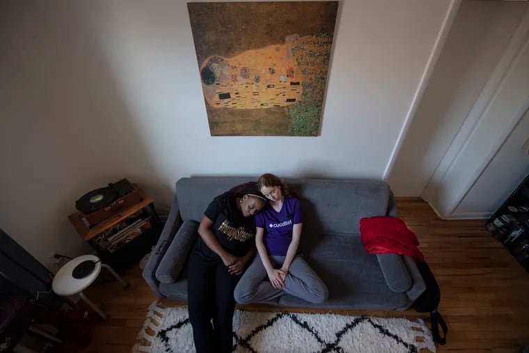 Ivy Dremon, right, a so-called cuddlist, cuddles in her South Philadelphia apartment with her client, Rashida, who didn't want her last name used. Ivy is paid to embrace and snuggle with people in non-sexual ways.