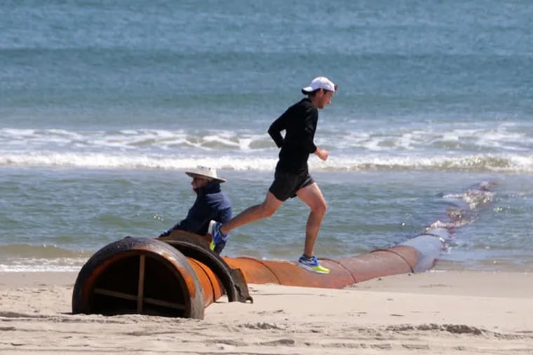 No obstacle: A runner on the beach at Ocean City hops over a dredge pipe that has been put in place on the beach at 43d Street. (CURT HUDSON)