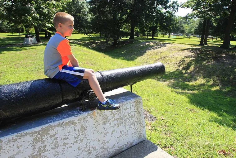 Luke Janofsky, 7, looks over the old trenches from the battlefield as he sits on a cannon. His mother, Jennifer Janofsky, is a Rowan history professor and Red Bank Battlefield curator.