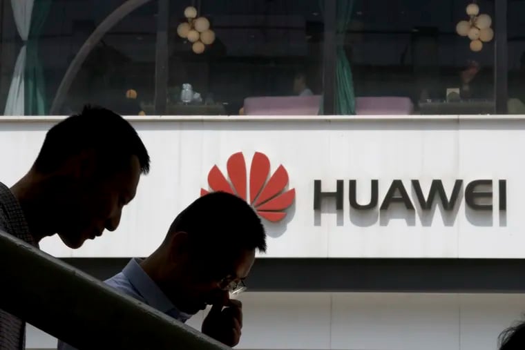 Chinese men pass by a Huawei retail shop in Beijing. Huawei Technologies is the world's biggest maker of network gear, the No. 2 smartphone manufacturer, and a champion of Chinese industry. (AP Photo/Ng Han Guan)