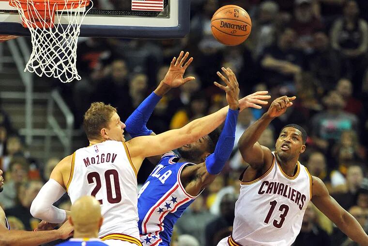 Philadelphia 76ers forward Nerlens Noel (4) and Cleveland Cavaliers center Timofey Mozgov (20) and forward Tristan Thompson (13) go for a rebound during the second quarter at Quicken Loans Arena.