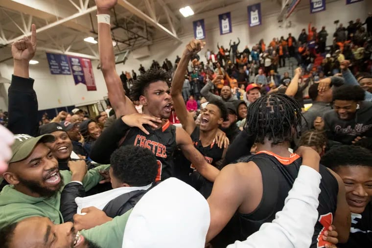 Chester players and fans storm the court after Zahmir Carroll (not pictured) made a last second shot to defeat Gratz in a second round game of the PIAA Class 6A boys' basketball state tournament. Karell Watkins is center.