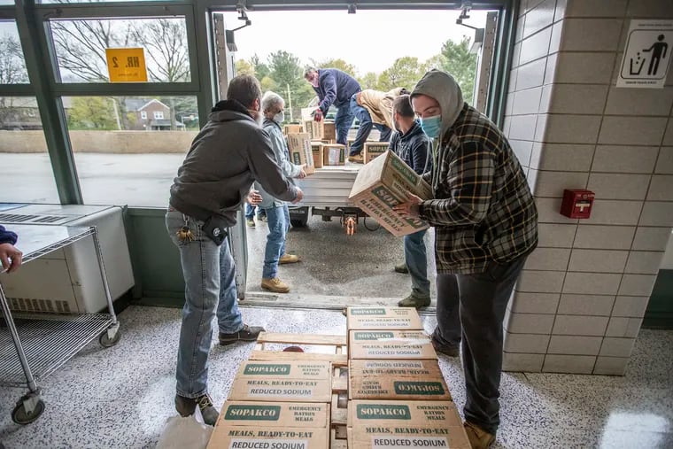 Employees of Upper Darby stack loose boxes of MRE meals onto a palette so they can be moved into the cafeteria of Drexel Middle School where they will be stored until they can be distributed in Delaware County, on April 21, 2020. PA National Guard delivered upwards of 15,000 meals to Drexel Hill Middle School, to be distributed to food pantries and homeless shelters.