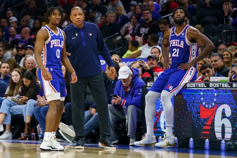Philadelphia 76ers head coach Doc Rivers, center, talks with Tyrese Maxey, left, as Joel Embiid, right, looks on.