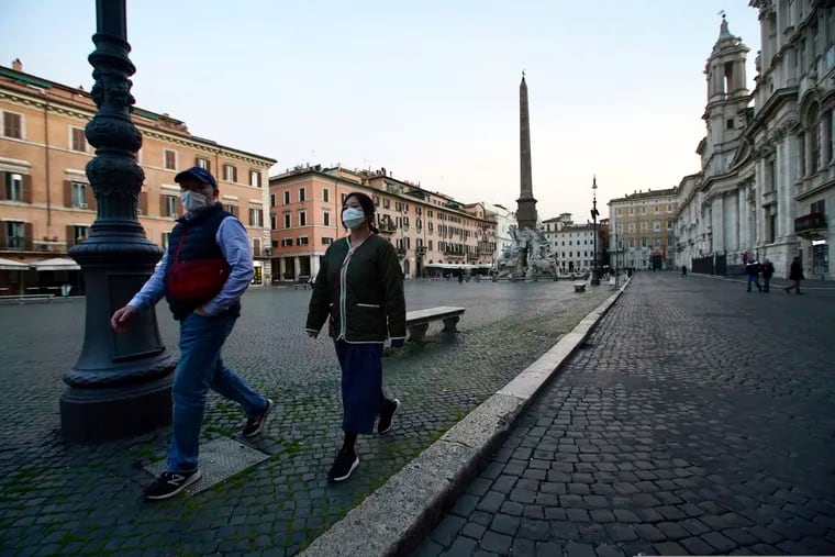 Two people walk in Rome's Piazza Navona, deserted, on March 10, 2020. For most people, the new coronavirus causes only mild or moderate symptoms, such as fever and cough. For some, especially older adults and people with existing health problems, it can cause more severe illness, including pneumonia. (AP Photo/Andrew Medichini)