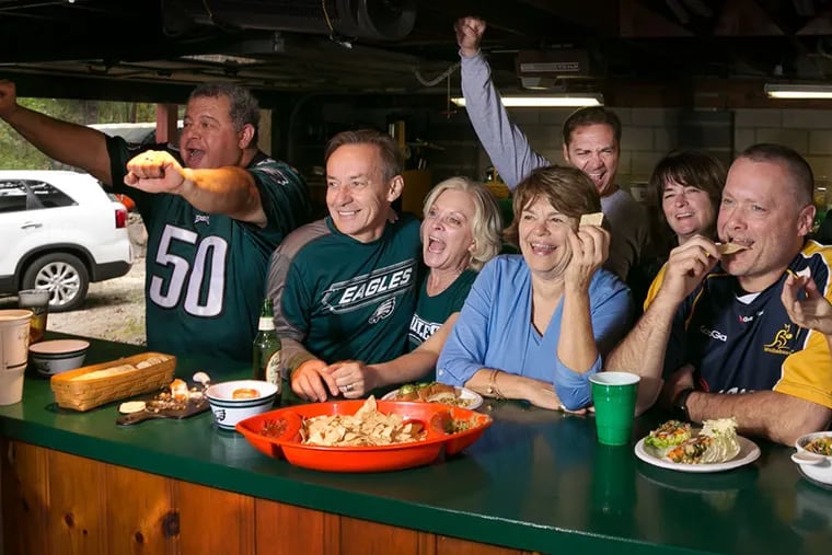 The home team cheers the Eagles to victory at the man cave party in the Medford home of Maurice "Mo Man" Perez (left) and Lauralee Dobbins. (Donna Connor/For the Daily News)