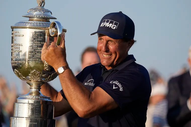 Phil Mickelson holds the Wanamaker Trophy after winning the PGA Championship golf tournament. He earned $2.16 million for himself and $300k for a bettor in New Jersey.
