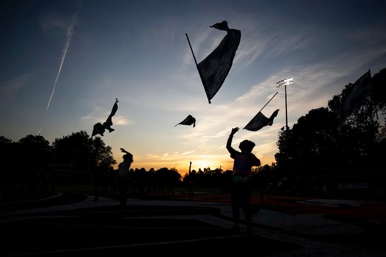 The marching band color guard toss their flags up during practice after school at Marple Newton High School on Wednesday, Sept. 25, 2019.