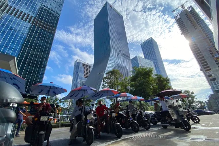 Men on electric bikes wait for riders near land developer Evergrande's headquarters in Shenzhen, China, Friday, Sept. 24, 2021. Mainland equities just entered their first bear market since Donald Trump’s trade war. Shares in Hong Kong had their worst week in five months. (AP Photo/Ng Han Guan)