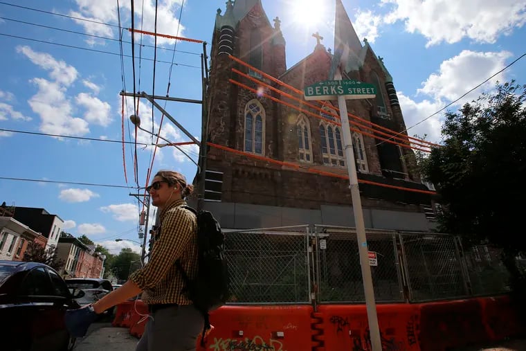 A pedestrian walks past the St. Laurentius Church on 1600 E. Berks Street in Fishtown in 2021. Because of its proximity to rowhouses, the church will be torn down by hand.