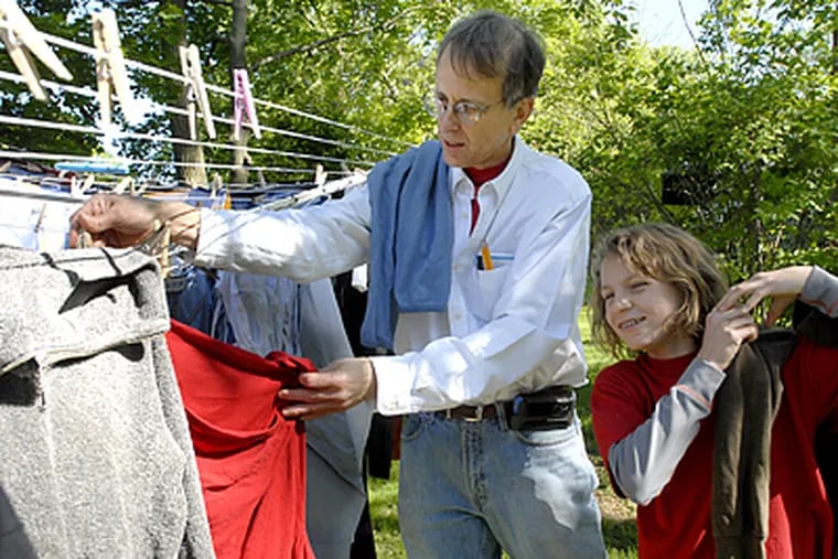 Steve Oliver and his daughter Maddie Oliver, 10, hang out their laundry to dry in their yard. (April Saul/Inquirer)