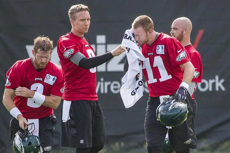 Eagle quarterback Nick Foles holds onto a towel as Carson Wentz wipes the sweat off his face.