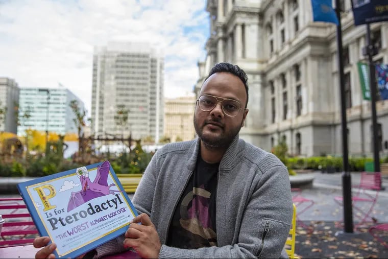 Raj Haldar, known by his rap name Lushlife, poses for a portrait with his new children's book, "P Is for Pterodactyl: The Worst Alphabet Book Ever," outside of City Hall on Wednesday, Nov. 7, 2018.