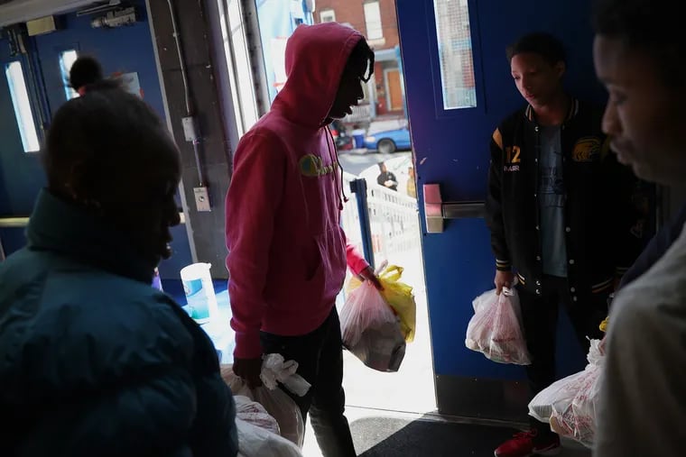 Keydre Cannon (center), 17, his siblings, and their mother, Kenya Cannon (left) leave after picking up free meals at Mastery Charter Shoemaker in West Philadelphia on Thursday, April 2, 2020. Parents are able to pick up meals for kids at a number of local schools while they are closed due to the coronavirus pandemic.