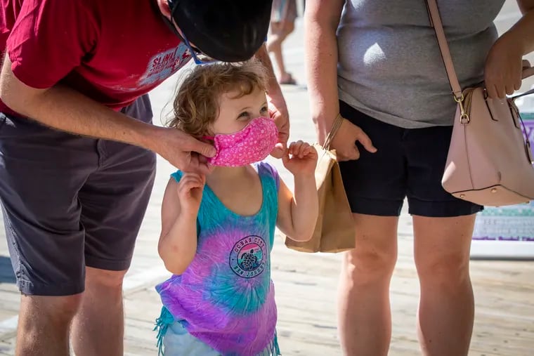 Chris Keiper of Pitman, NJ, puts a mask on his daughter Quinn, 4, before going to eat indoors at Manco & Manco on the boardwalk in Ocean City, NJ on Labor Day, Sept. 7, 2020.