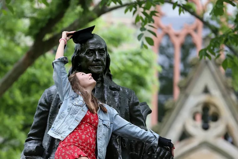Penn graduate Aife Mejza puts her cap on top of the Ben Franklin statue on campus in Philadelphia in May 2020.