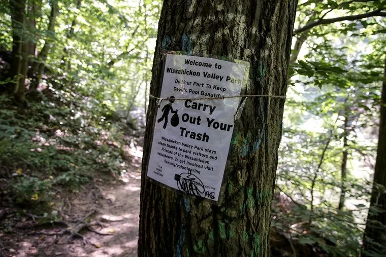 Signs asking visitors to carry out their trash are posted along the trail in Wissahickon Valley Park on Aug. 22, 2019.