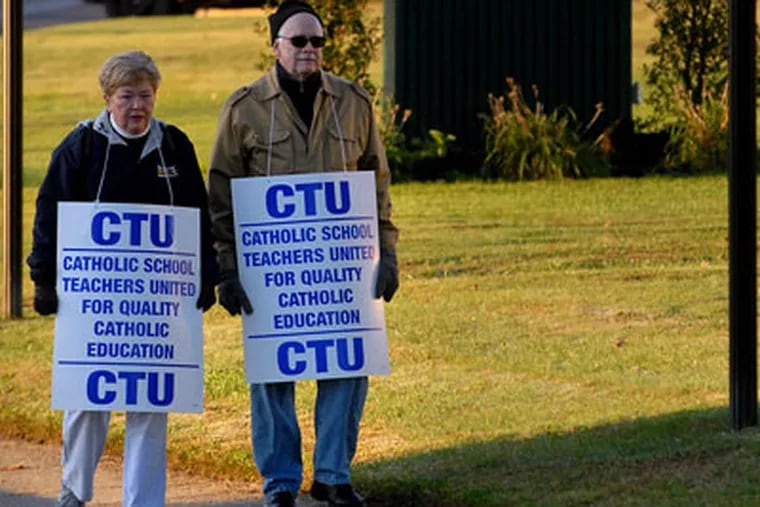 Camden Catholic High School teachers Vicki Trainor, left, and John Oakes picket outside the school as students arrive for classes this morning. (TOM GRALISH / Staff Photographer)