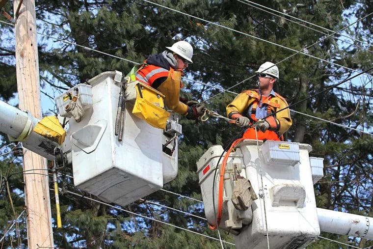 PECO linemen Shawn Cochran, left, and CJ Sclafani, right, work to repair lines that came down on Union Meeting Road in Blue Bell during a storm.