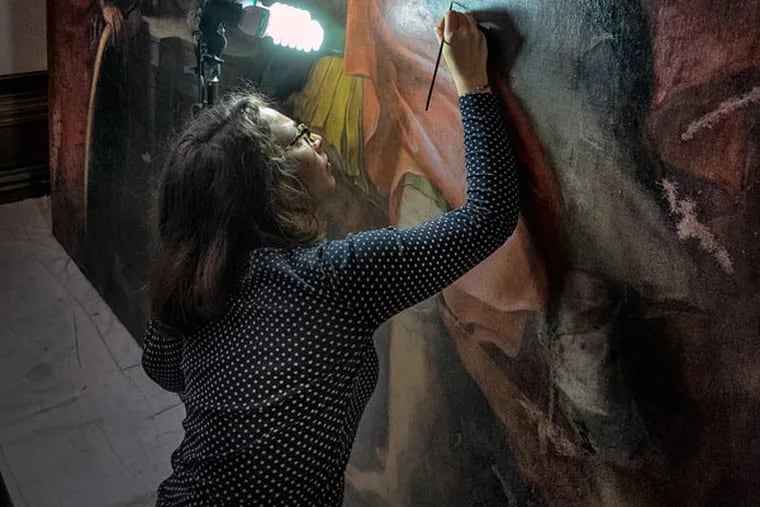 Using X-rays, Villanova scholars have revealed a painting beneath the university's 17th-century masterpiece, da Cortona's "Triumph of David." Here, Serena Vella works on the painting as part of a restoration. (ED HILLE / Staff Photographer )