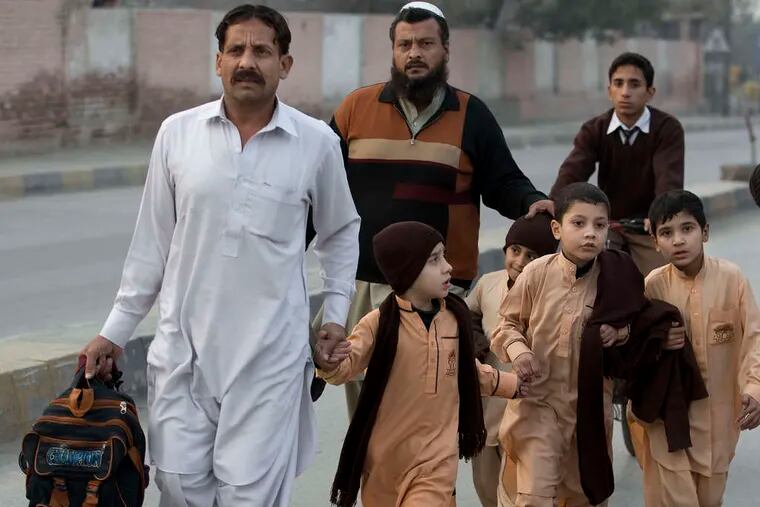 Fathers escort their children outside the school in Peshawar. The government declared three days of mourning.