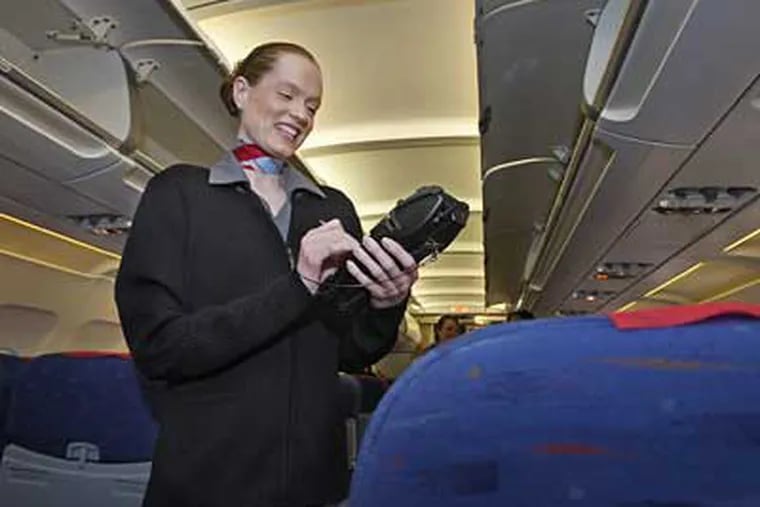 Aboard a USA3000 flight to Fort Myers, Fla., Laura Korpel, lead flight attendant, uses a handheld card reader to swipe credit or debit cards for such purchases as cocktails and headphones. (Michael S. Wirtz / Staff Photographer)