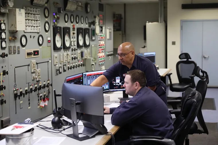 Control room operators Scott Trezise, front, and Dion Montalvo work at the Vicinity Energy cogeneration plant in Philadelphia's Grays Ferry section on Friday, Jan. 31, 2020. The plant, originally opened by Philadelphia Electric, produces electricity and steam for heating Center City buildings.