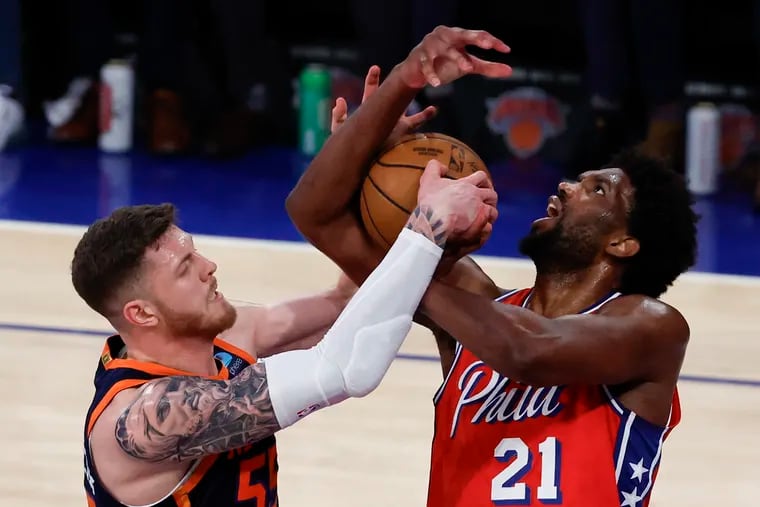 Sixers center Joel Embiid goes after the basketball against New York's Isaiah Hartenstein (left) during Game 2.