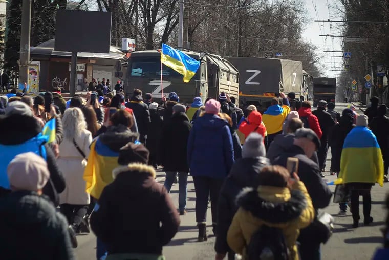 People with Ukrainian flags walk towards Russian army trucks during a rally against the Russian occupation in Kherson, Ukraine, Sunday, March 20, 2022.
