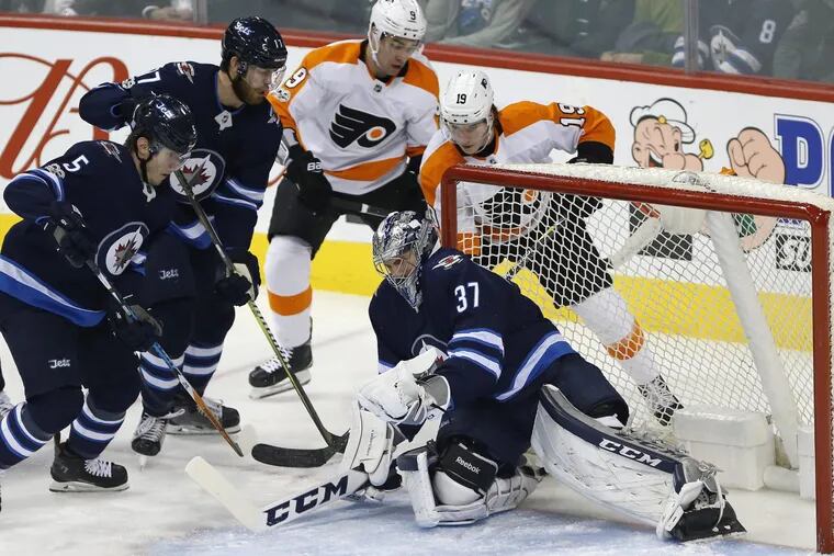 Winnipeg Jets goaltender Connor Hellebuyck (37) stops a shot by Flyers Nolan Patrick (19) during first-period NHL hockey game action in Winnipeg, Manitoba, Thursday, Nov. 16.
