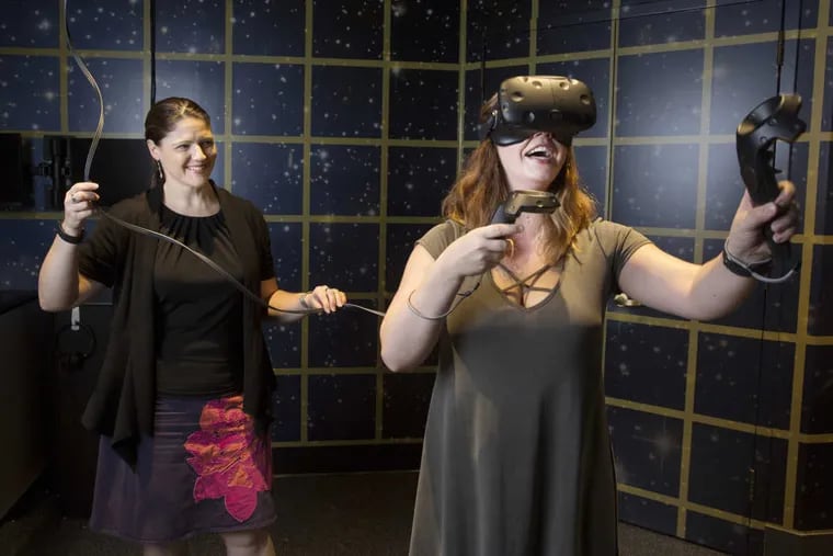 Chief Digital Officer Susan Poulton, left, works with Jacki Wahlquist, right, development coordinator at the Franklin Institute, as she tries out the HTC Vive Virtual Reality Head Mounted Display at the Franklin Institute.