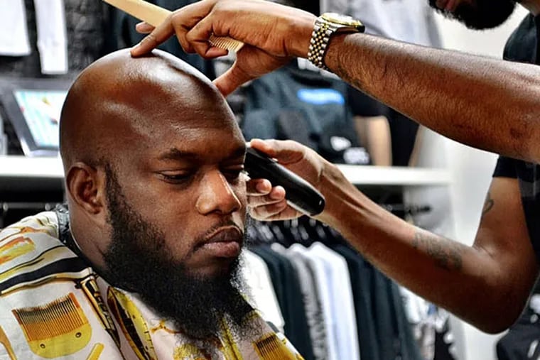 Barber Andre Scott, trimming up Freeway's fringe, says he has been using the product for several months. (Kaseem Green)