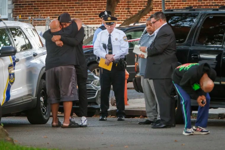 Men comfort one another at the scene of a quadruple shooting on the 6100 block of Shelbourne Street in Philadelphia early Monday.