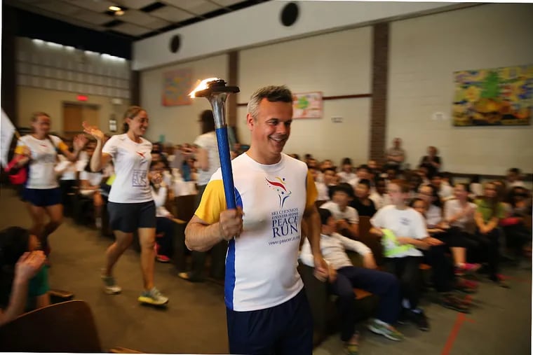 Devashishu Torpy, of Great Britain, holds the torch as he leads his group from the Sri Chinmoy Peace Run into the McCall school auditorium during a visit to Philadelphia.