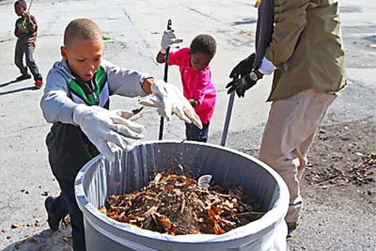 Aquill Foster, 8, dumps trash and leaves into the trash on the playground of Stephen Girard Elementary school in South Philly.  Marriott Hotel employees and their family members and local kids of the neighborhood were there to clean up the place.