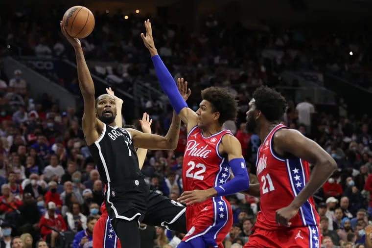 Kevin Durant, left, of the Nets shoots against Matisse Thybulle, center, and Joel Embiid, right,  of the Sixers during the second half of the Sixers' home opener at the Wells Fargo Center.