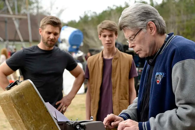 "Under the Dome" cast members Mike Vogel (left) and Colin Ford watch series executive producer Stephen King (right) fix the script.