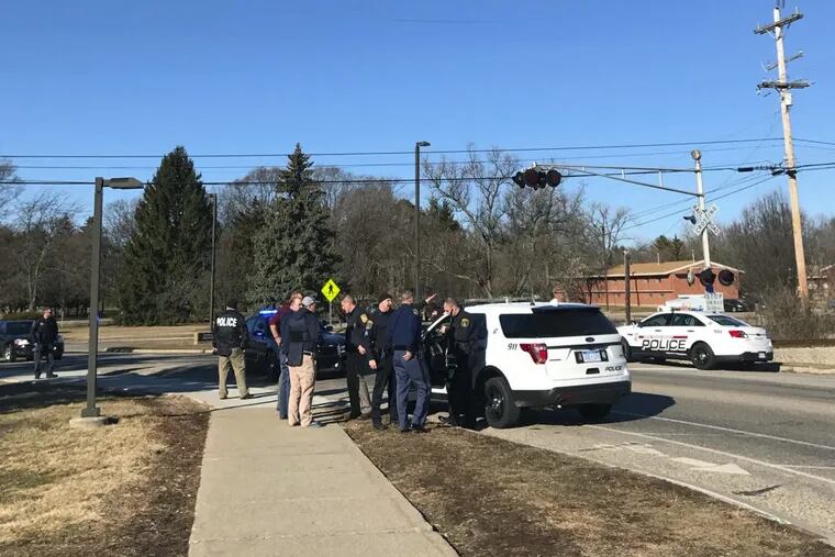 Authorities stand on the campus of Central Michigan University during a search for a suspect, in Mount Pleasant, Mich. School officials say police responded to a report of shots fired at a residence hall.