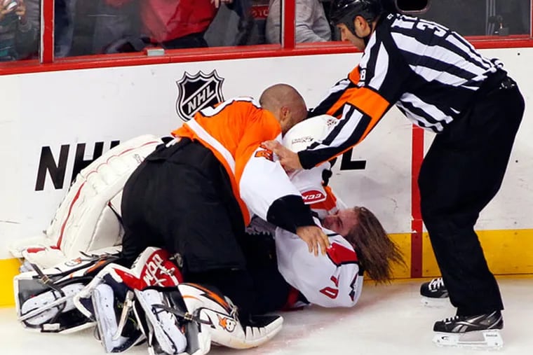 Linesman Francois St. Laurent, right, tries to pull Flyers goalie Ray Emery, top, off of Washington Capitals goalie Braden Holtby during a melee in the third period of an NHL hockey game Friday, Nov. 1, 2013, in Philadelphia. The Capital won 7-0. (Tom Mihalek/AP)