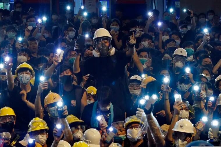 Protesters hold up mobile phone lights in front of police headquarters in Hong Kong, Friday, June 21, 2019.