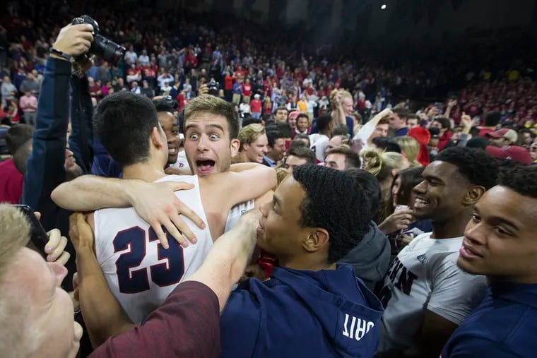 Max Rothschild, center, hugs Michael Wang, left of Penn as they celebrate after their 78-75 victory over Villanova at the Palestra on Dec. 11, 2018.    CHARLES FOX / Staff Photographer