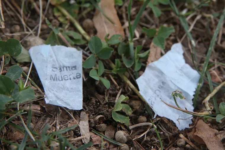 A glassine heroin bag with a "Santa Muerteâ" stamp, at left, sits on the lawn around McPherson Square Library in Philadelphia.