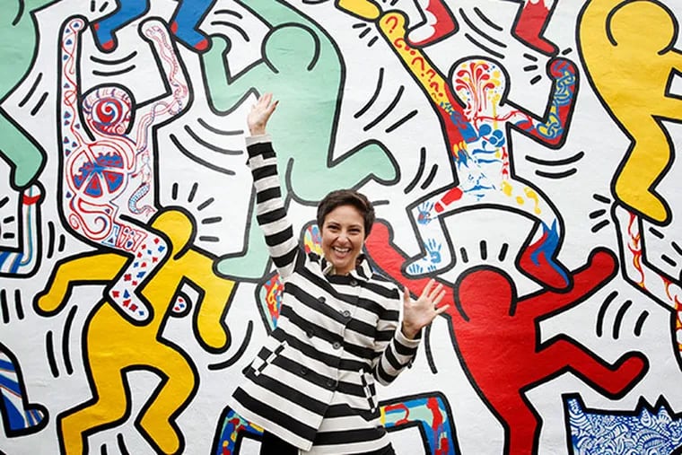 Erica Bryant, the home owner, mimics a keith Haring figure. "We The Youth," a Keith Haring mural originally created in 1987 at 22nd and Ellsworth Streets, has been restored by artists from the Mural Arts Program. ( MICHAEL S. WIRTZ / Staff  )