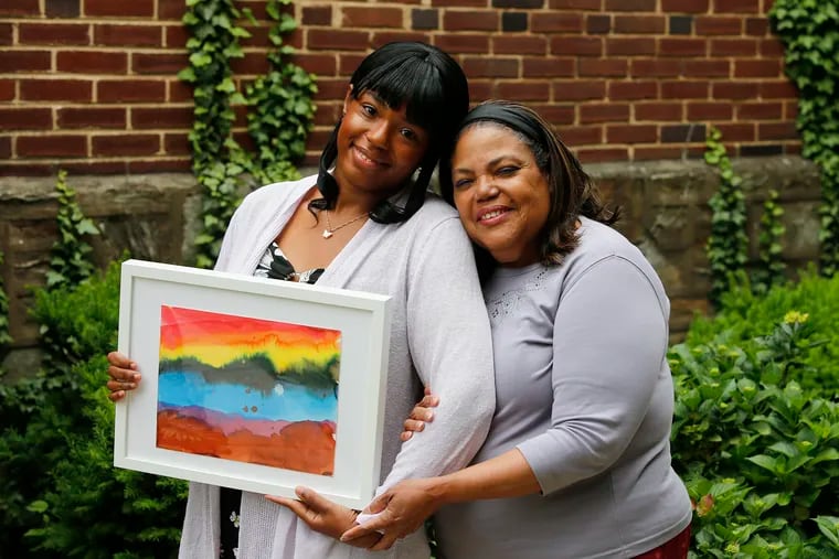 JoAnn Robinson (right) and her daughter Diamond Princess Franklin hold a gift the Double Rainbows Project presented them in memory their mother and grandmother, Ida Rebecca Robinson, who passed away from the coronavirus in April of 2020. The project has collected rainbows hand-drawn by city kids during the pandemic and is offering them to families who have lost loved ones to Covid-19.