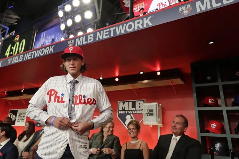 Alec Bohm puts on his Phillies jersey after being selected third overall Monday night at the MLB draft in Secaucus, N.J. 