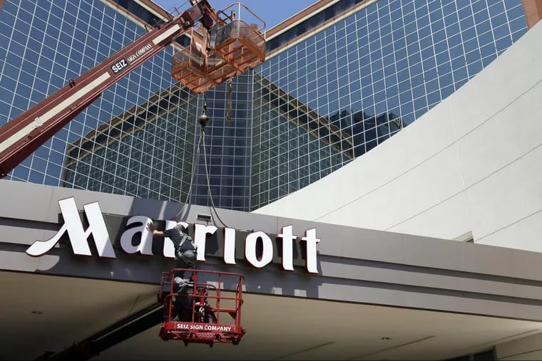 A man works on a new Marriott sign in front of the former Peabody Hotel in Little Rock, Ark. Marriott says the information of up to 500 million guests at its Starwood hotels has been compromised.