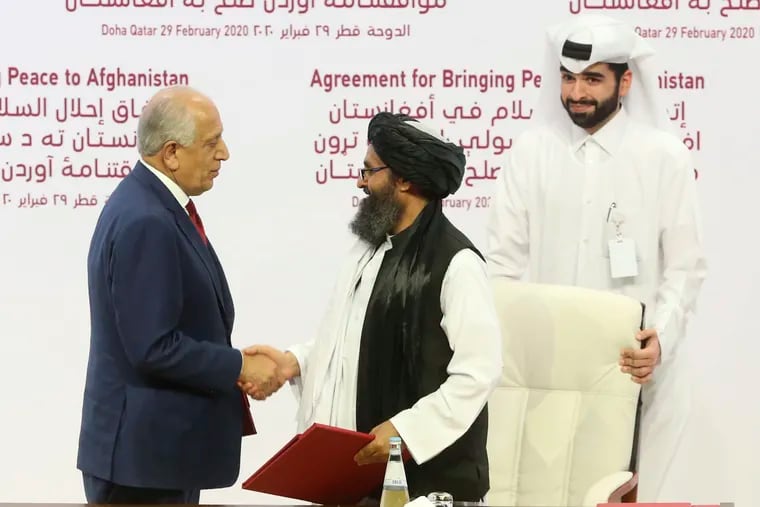 U.S. peace envoy Zalmay Khalilzad, left, and Mullah Abdul Ghani Baradar, the Taliban group's top political leader shack hands after signing a peace agreement between Taliban and U.S. officials in Doha, Qatar, Saturday, Feb. 29, 2020. The United States is poised to sign a peace agreement with Taliban militants on Saturday aimed at bringing an end to 18 years of bloodshed in Afghanistan and allowing U.S. troops to return home from America's longest war. (AP Photo/Hussein Sayed)