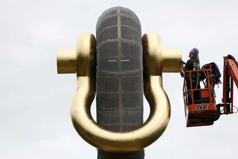 Don Kane, of Mariano Brothers Inc. places the last piece of the gold leaf shackle in place as installation is almost complete on sculptor Martin Puryear&#039;s 40-foot-tall &quot;Big Bling&quot; along Kelly Drive in Philadelphia, PA on May 24, 2017.